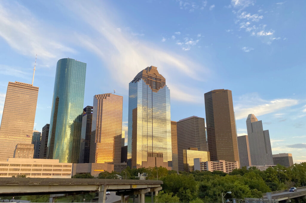 Downtown Houston Skyscraper buildings at sunset with view of cars on freeway in front. Texas, USA.